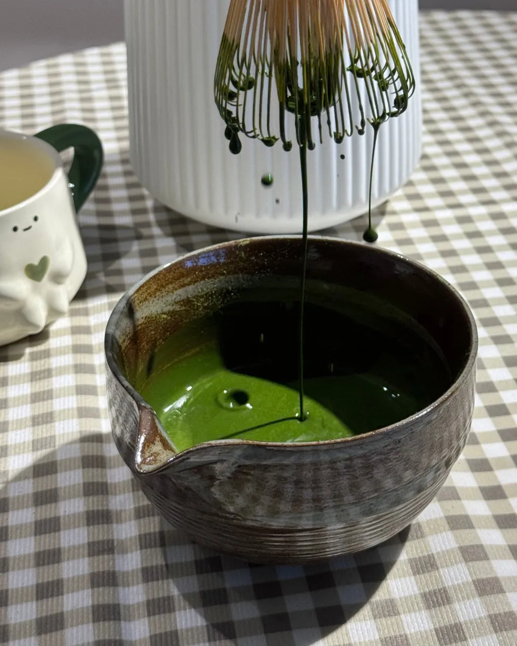 Whisking Chaboys matcha with a bamboo chasen in a ceramic bowl